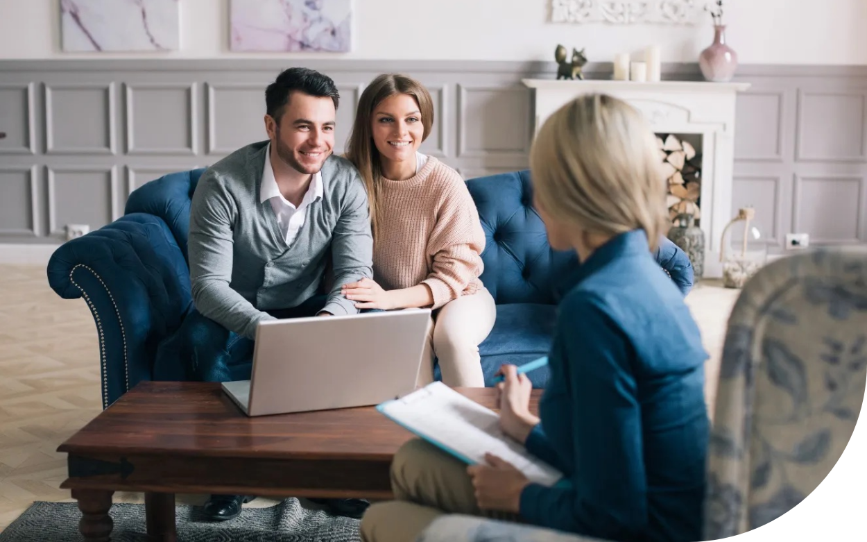 A man and a woman are sitting on a couch looking at a laptop.