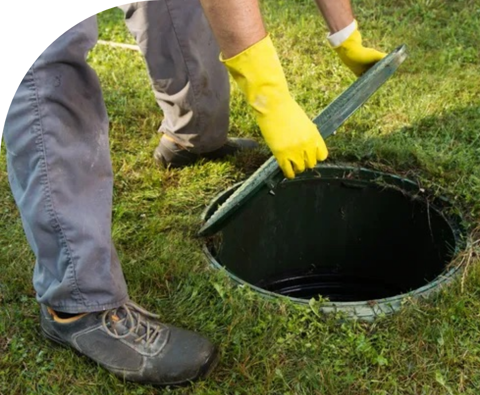 A person wearing yellow gloves is opening a manhole cover.