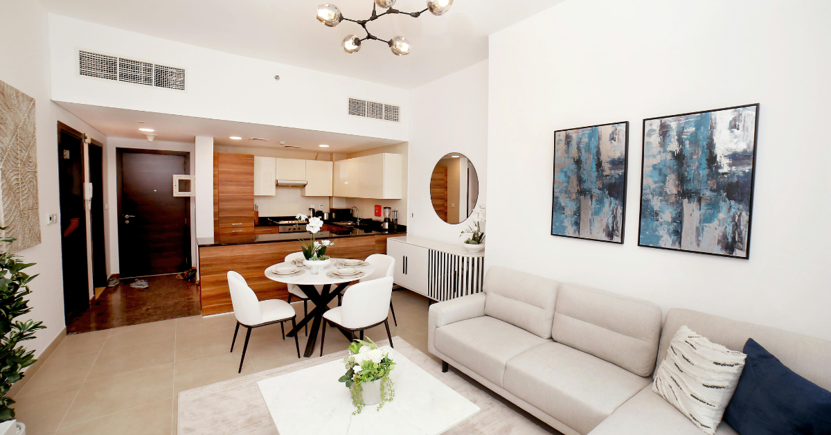 A living room with a couch , table and chairs and a kitchen in the background.