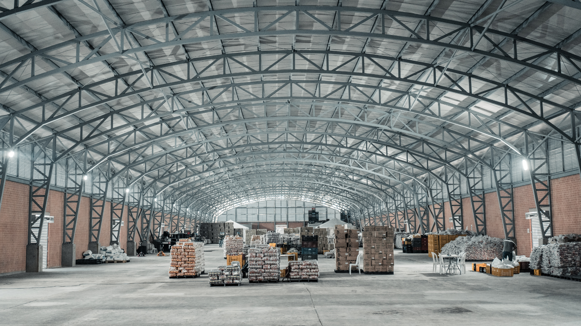 A large warehouse filled with lots of boxes under a metal roof.