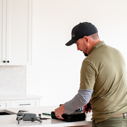 Man in cap and green shirt working on equipment on a white counter.