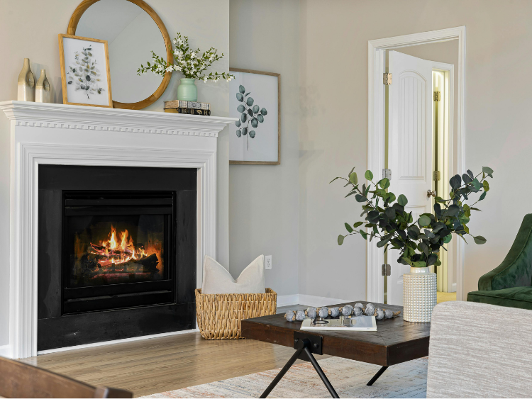 A person is sitting in front of a fireplace holding a cup of coffee.