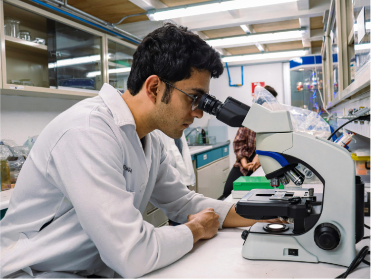 Man in lab coat looks into a microscope in a laboratory.