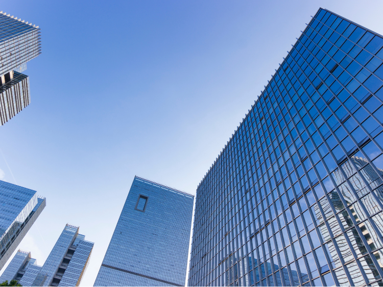 Modern skyscrapers with glass windows against a bright blue sky.