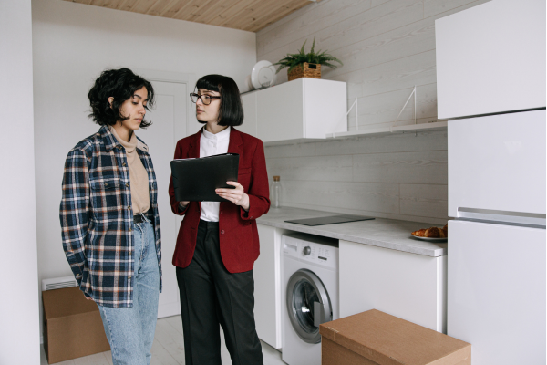 A realtor leads a couple through a newly constructed, empty apartment.
