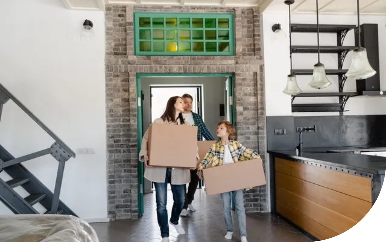 A family is carrying cardboard boxes into a new home.
