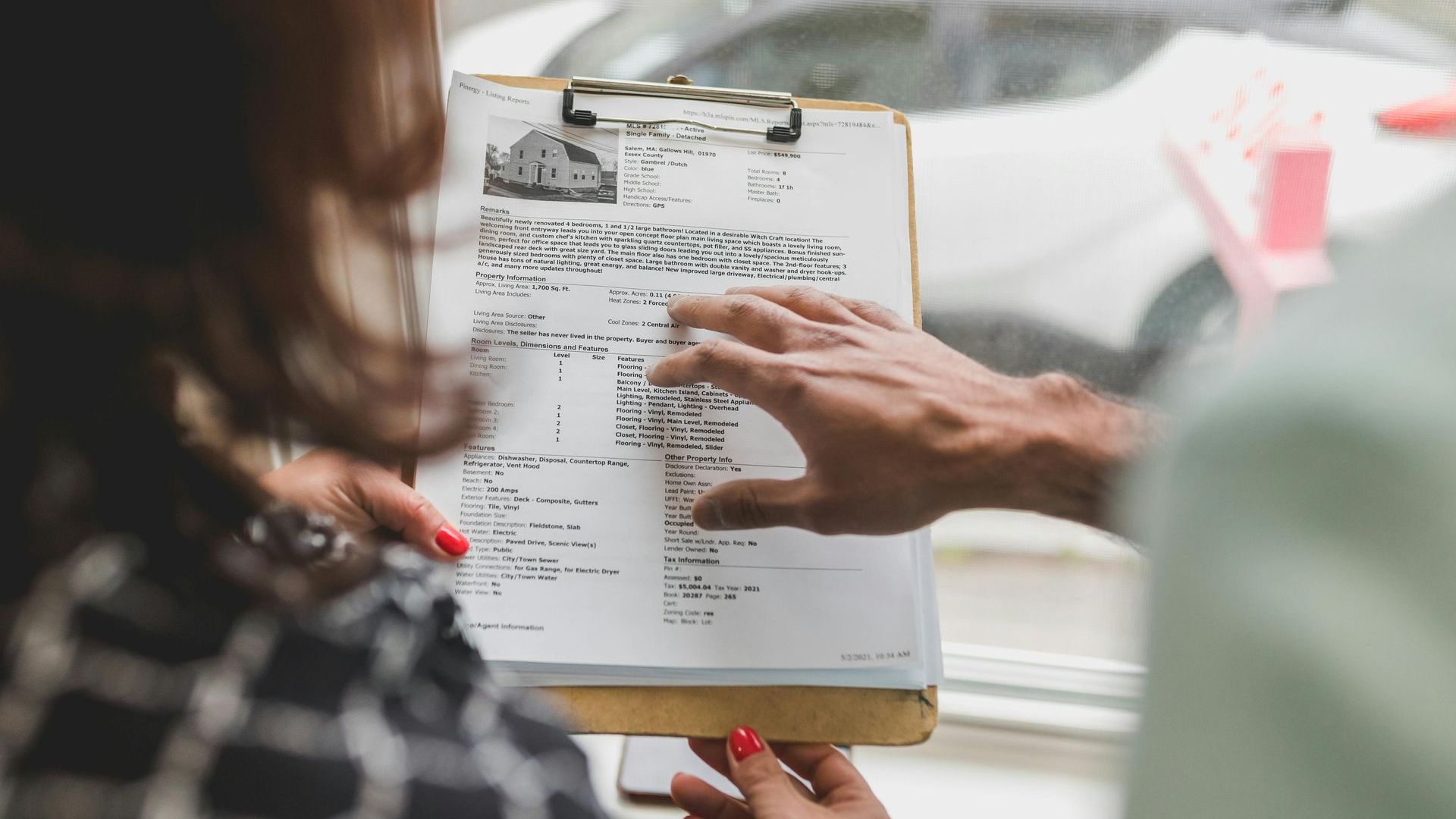A woman is holding a clipboard with a man pointing at it.