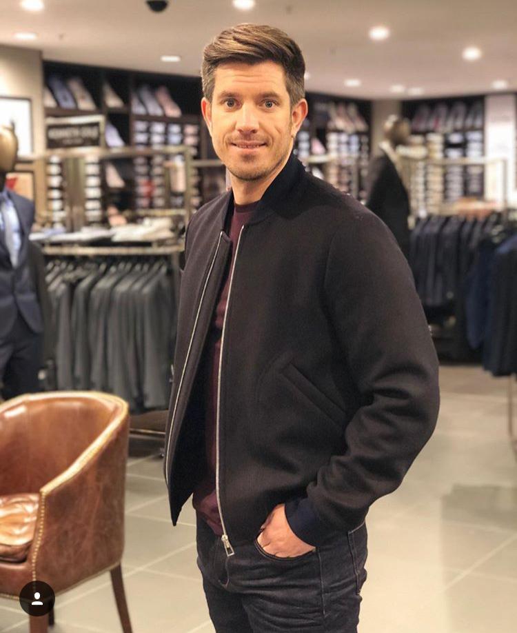 A man in a black jacket is standing in a store