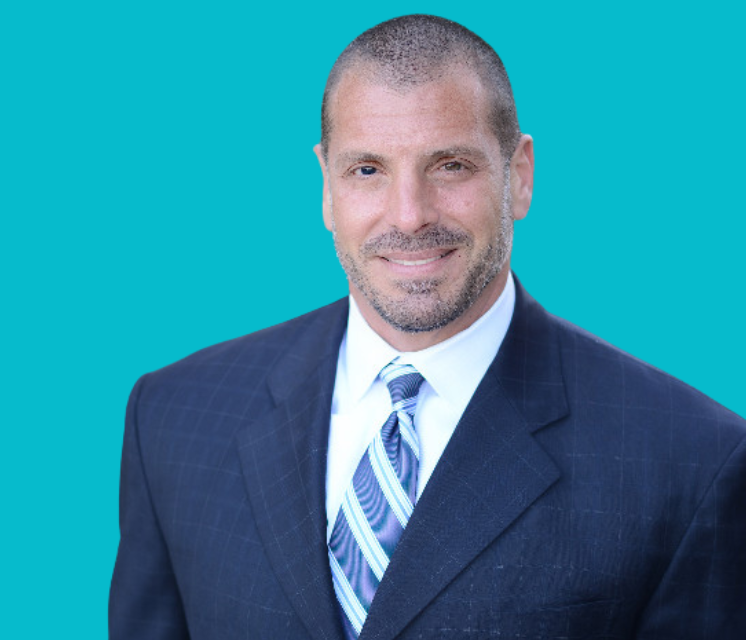 A man in a suit and tie is smiling for the camera.