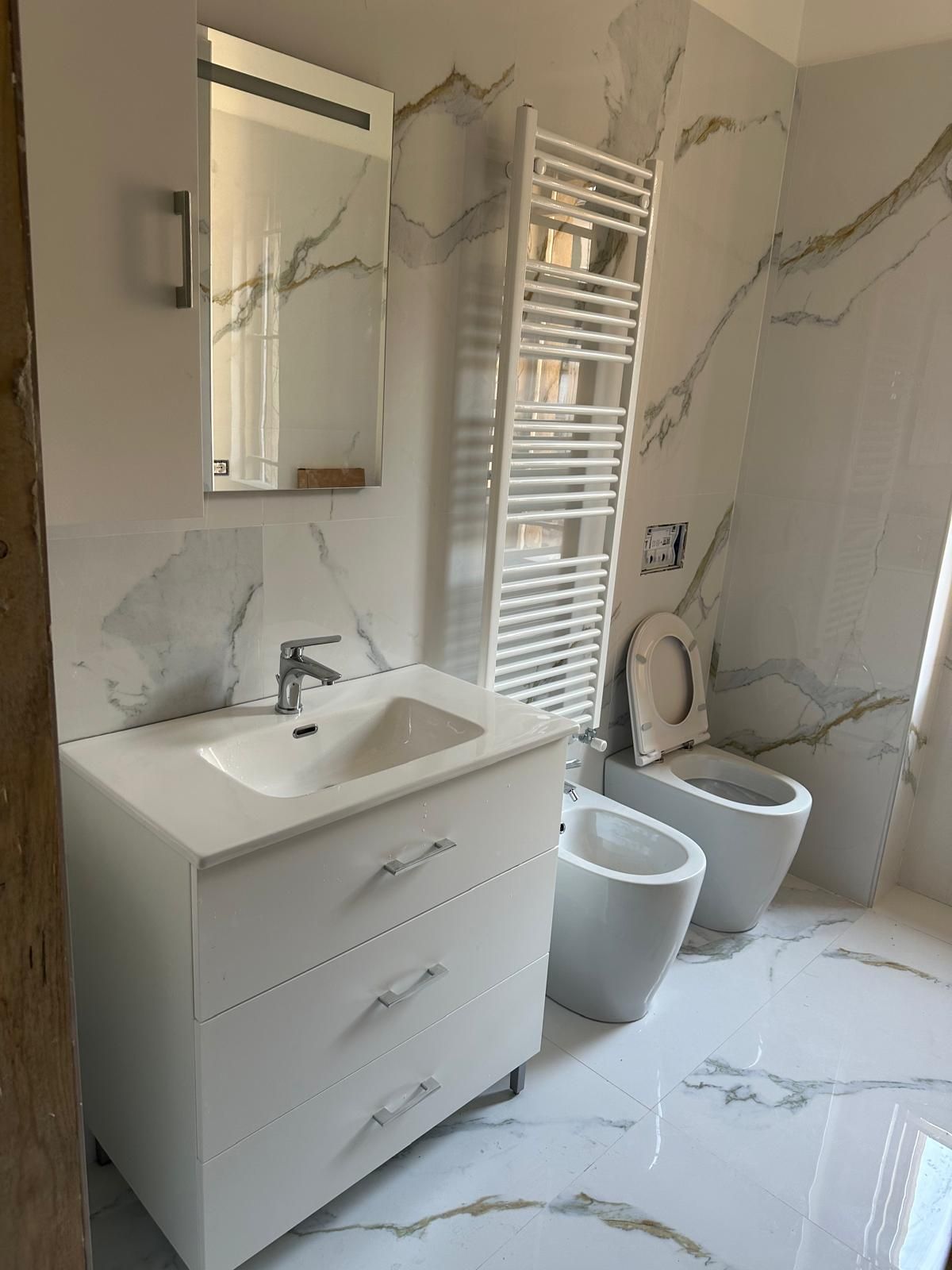 Un bagno con lavandino, water, bidet e specchio.