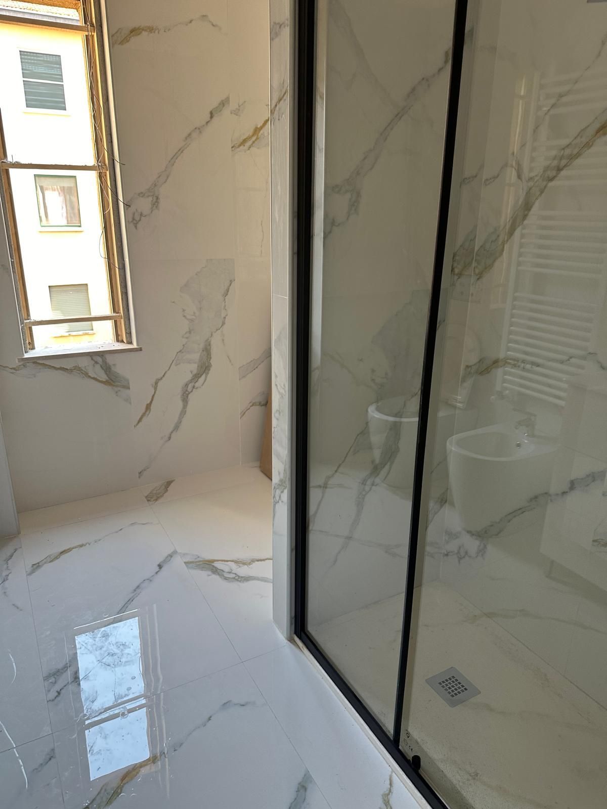 Un bagno con piastrelle di marmo e cabina doccia.