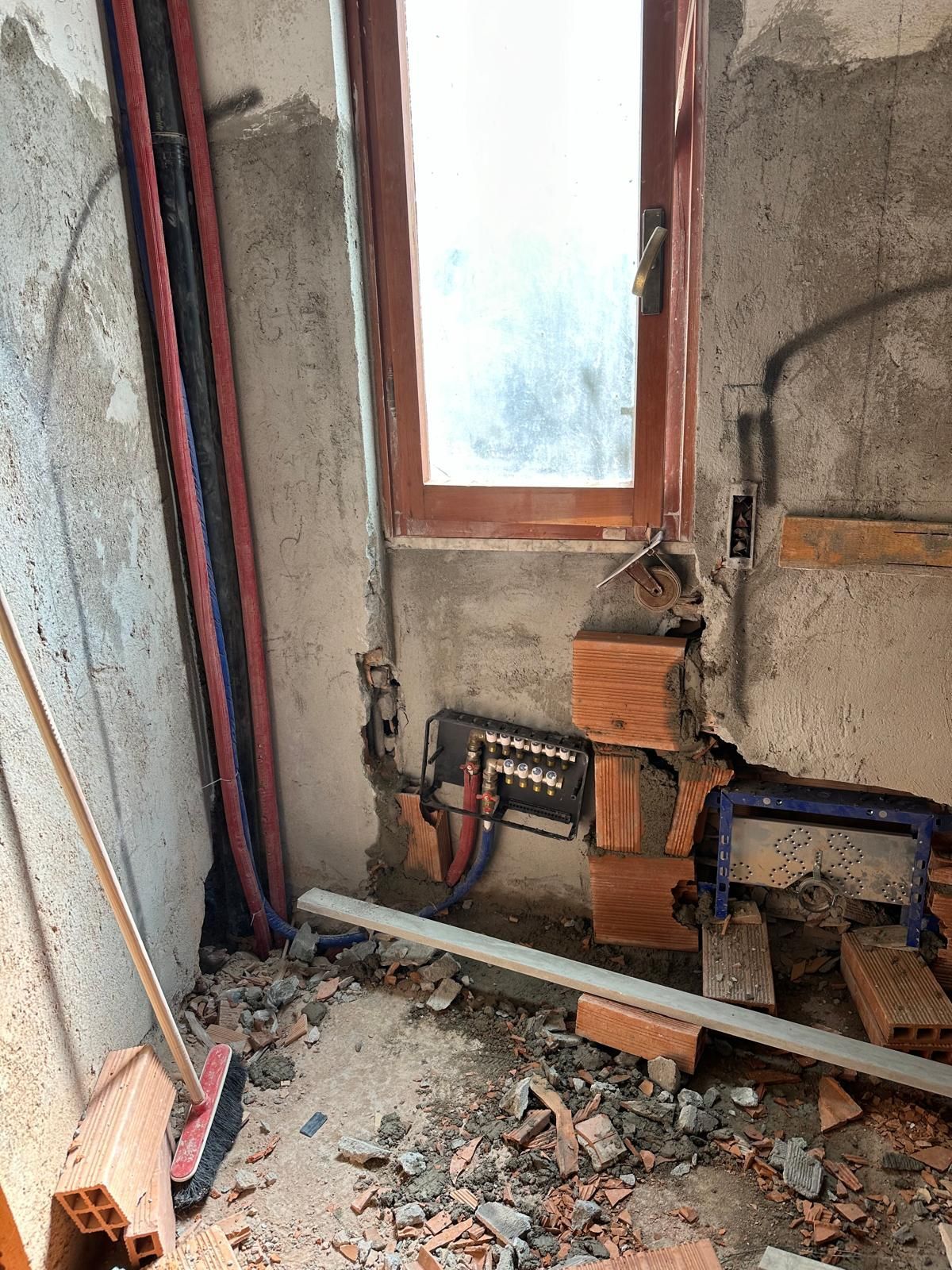 Una stanza con una finestra e un sacco di mattoni sul pavimento.