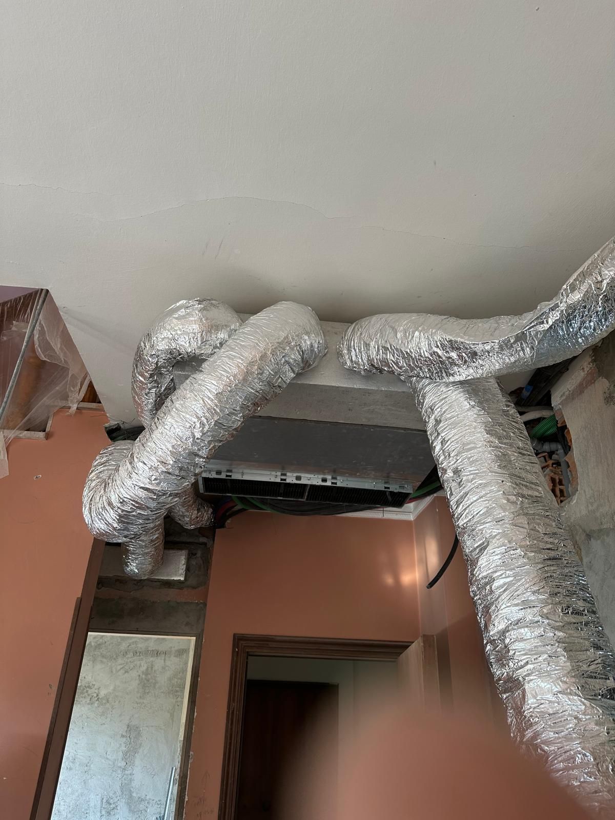 Un mucchio di condotti pendono dal soffitto di una stanza.