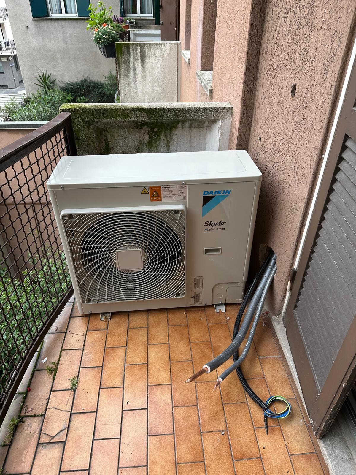 Un condizionatore bianco è posizionato su un balcone accanto a un edificio.