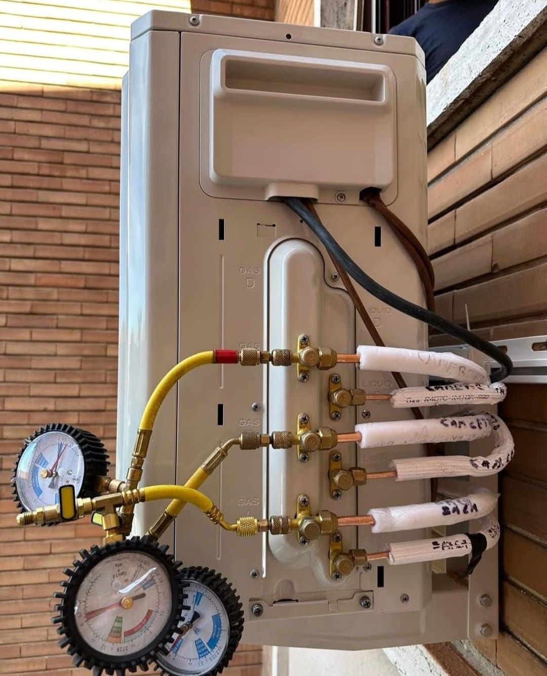 Un condizionatore bianco viene installato su un muro di mattoni.