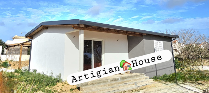 Una piccola casa bianca moderna con un tetto piatto grigio e la scritta 