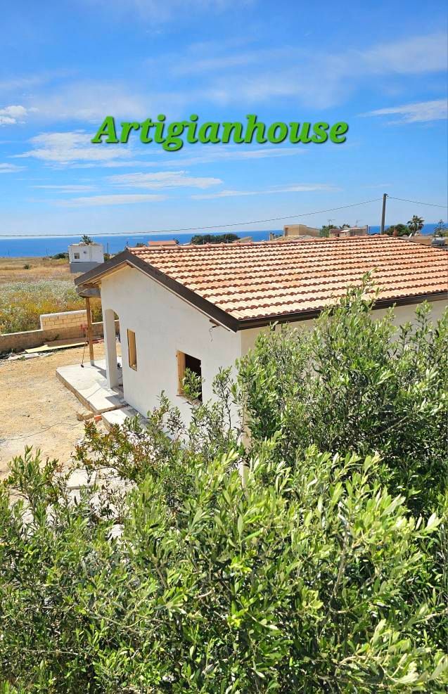 Edificio bianco con tetto di tegole rosse, immerso nel verde. Testo 