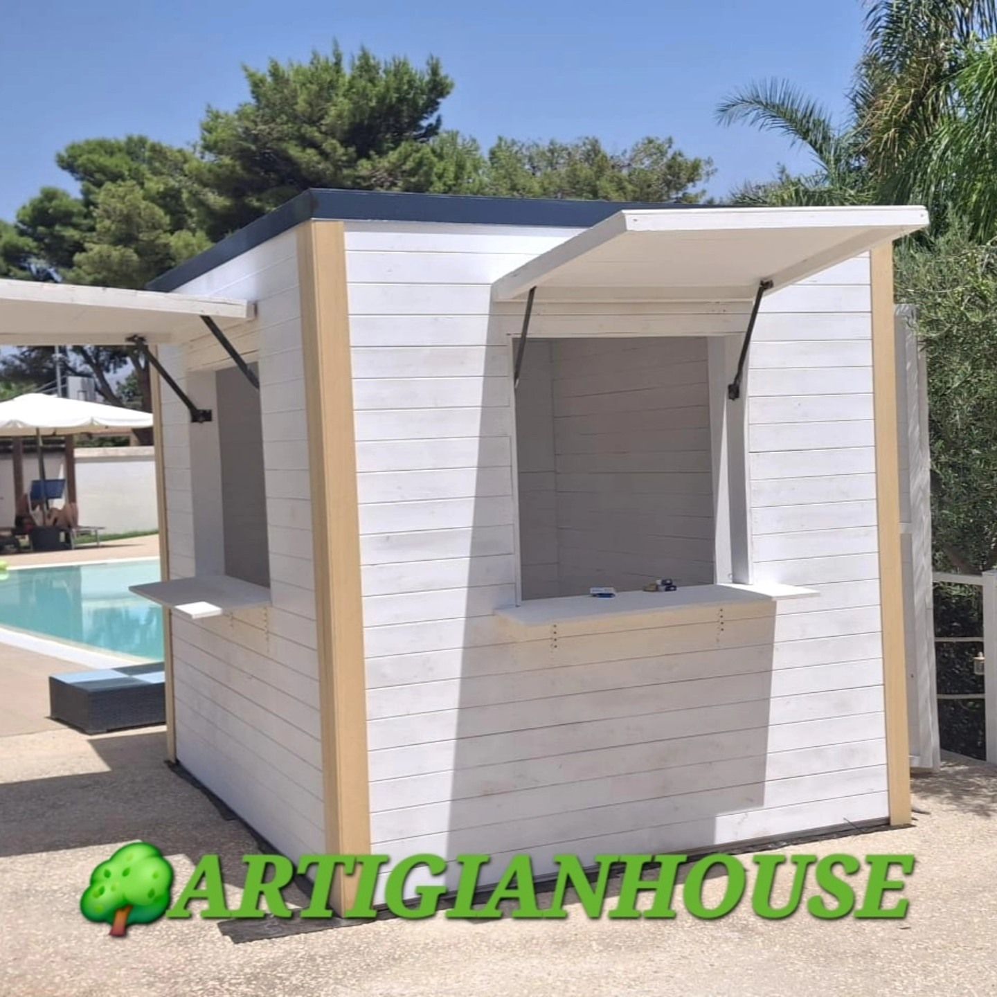 Bar all'aperto in legno bianco e marrone chiaro con finestre aperte per il servizio, accanto a una piscina.