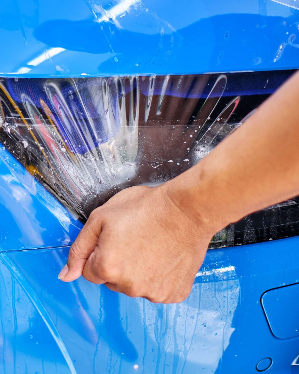 A man is cleaning the wheel of a black car with a sponge.