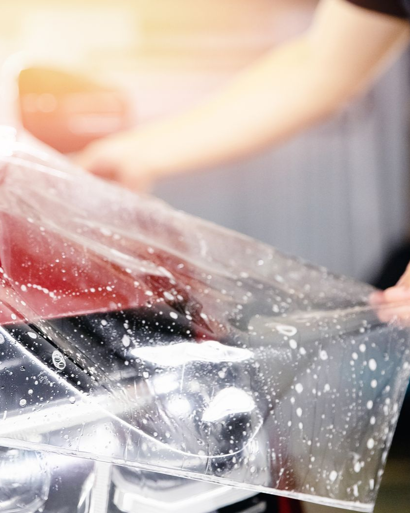 A person is cleaning a blue car with an orange towel