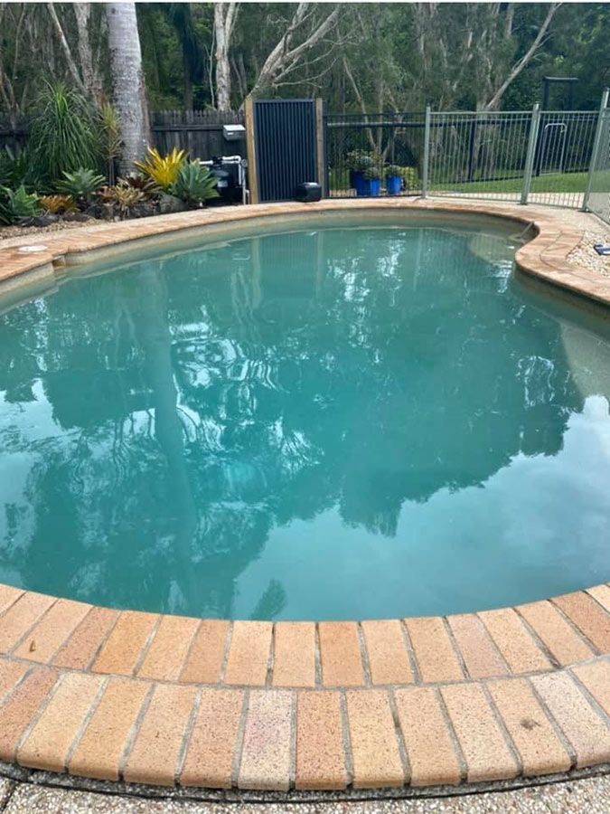 A Large Swimming Pool With A Brick Border — Landsborough Pool Supplies & Service in Landsborough, QLD