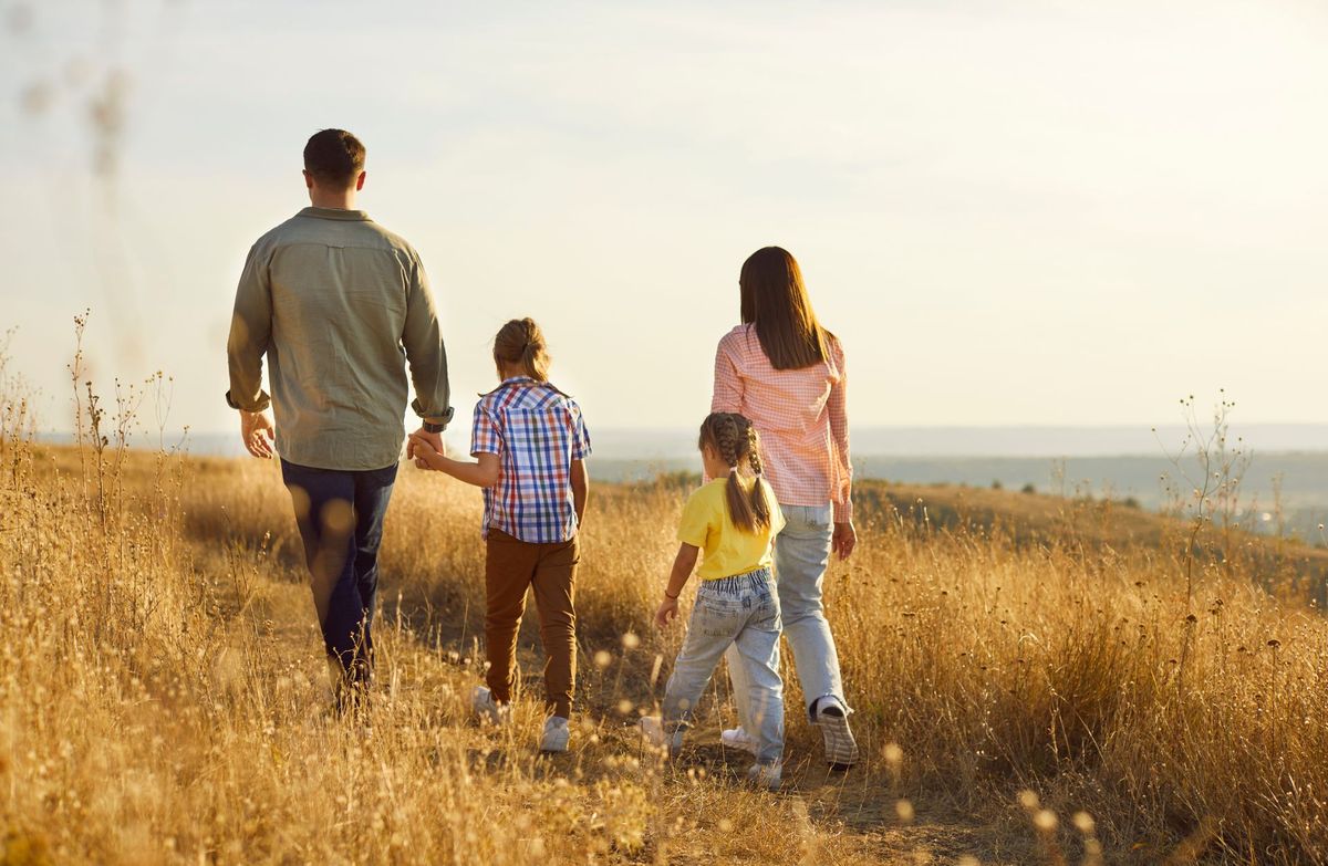 Family walking through a golden grassy field at sunset