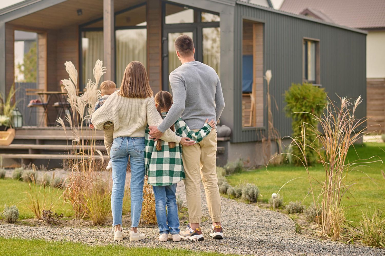 A family is posing for a picture in front of their new home.
