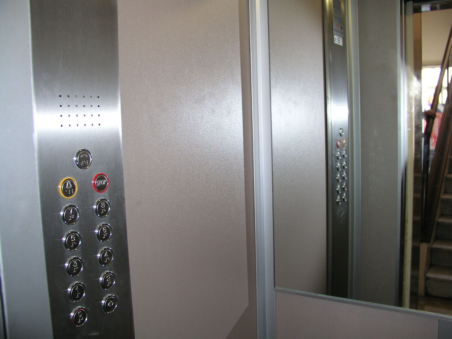 Un ascensore in acciaio inox con pulsanti e uno specchio