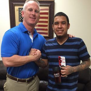 Two men are posing for a picture in front of an american flag.