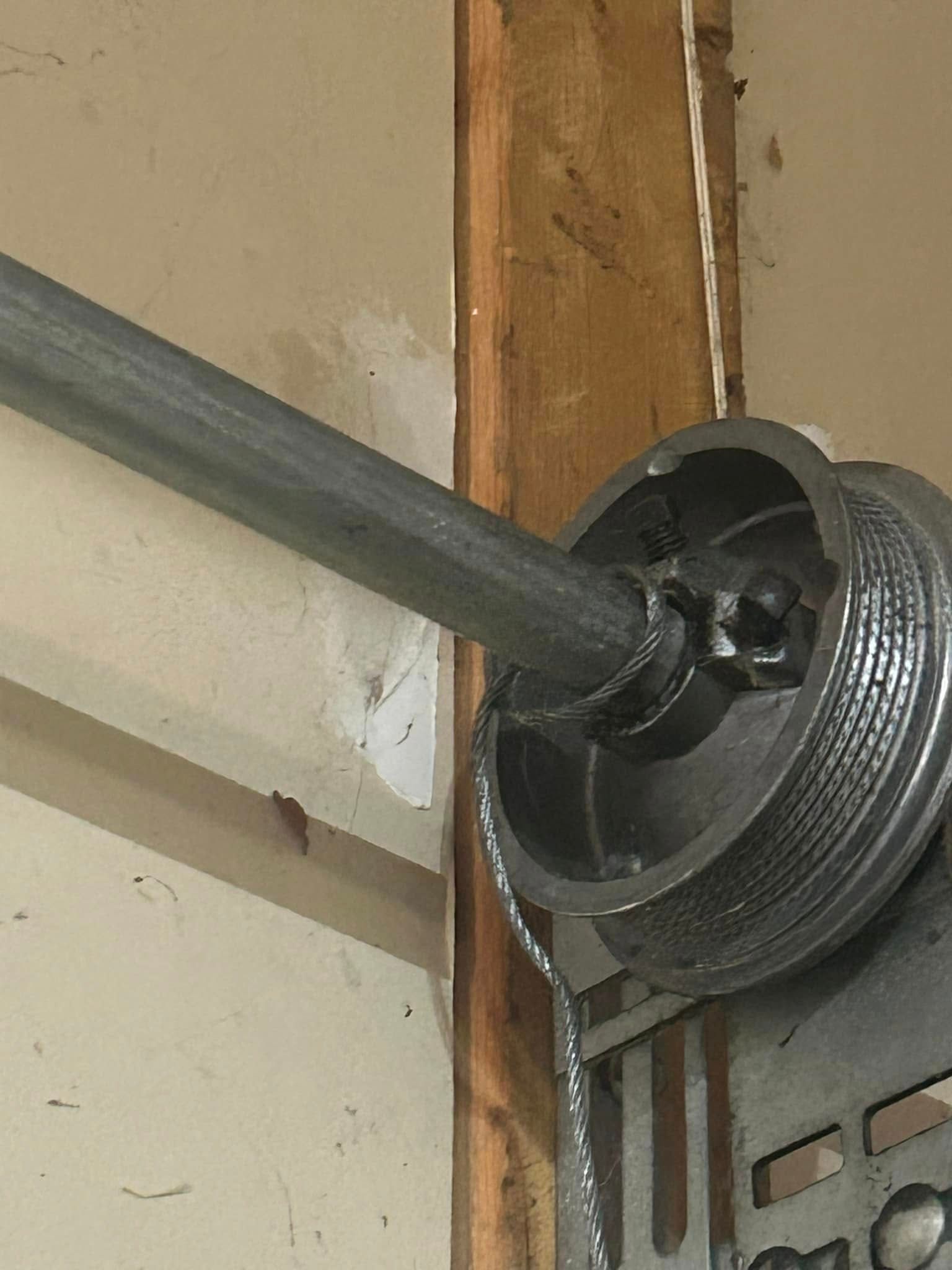 Garage door torsion spring assembly, with a metal drum and cable attached.