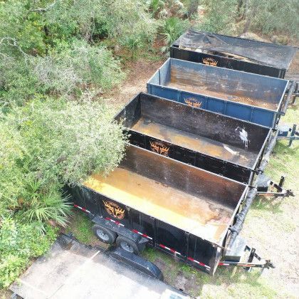 A row of dump trailers are parked next to each other in a field.