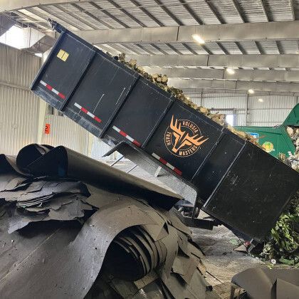 A dumpster is being filled with scrap metal in a warehouse.