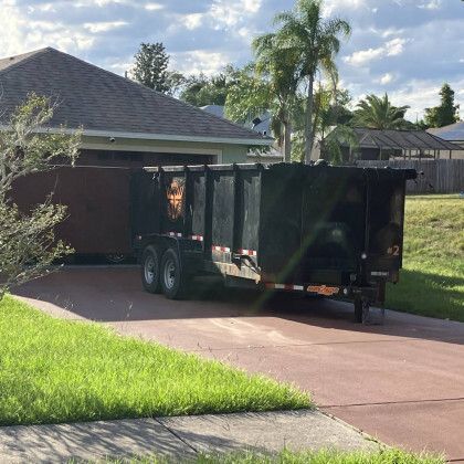 A dumpster is parked in a driveway in front of a house.