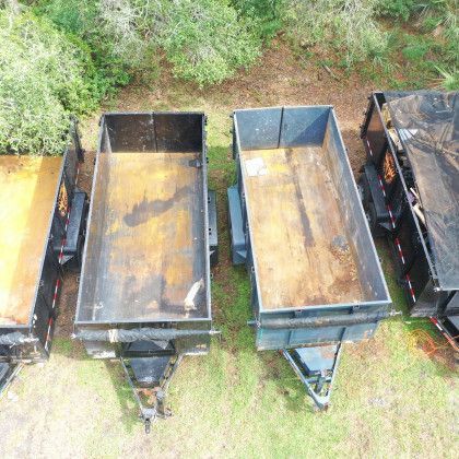 A group of dump trailers are parked next to each other in a field.