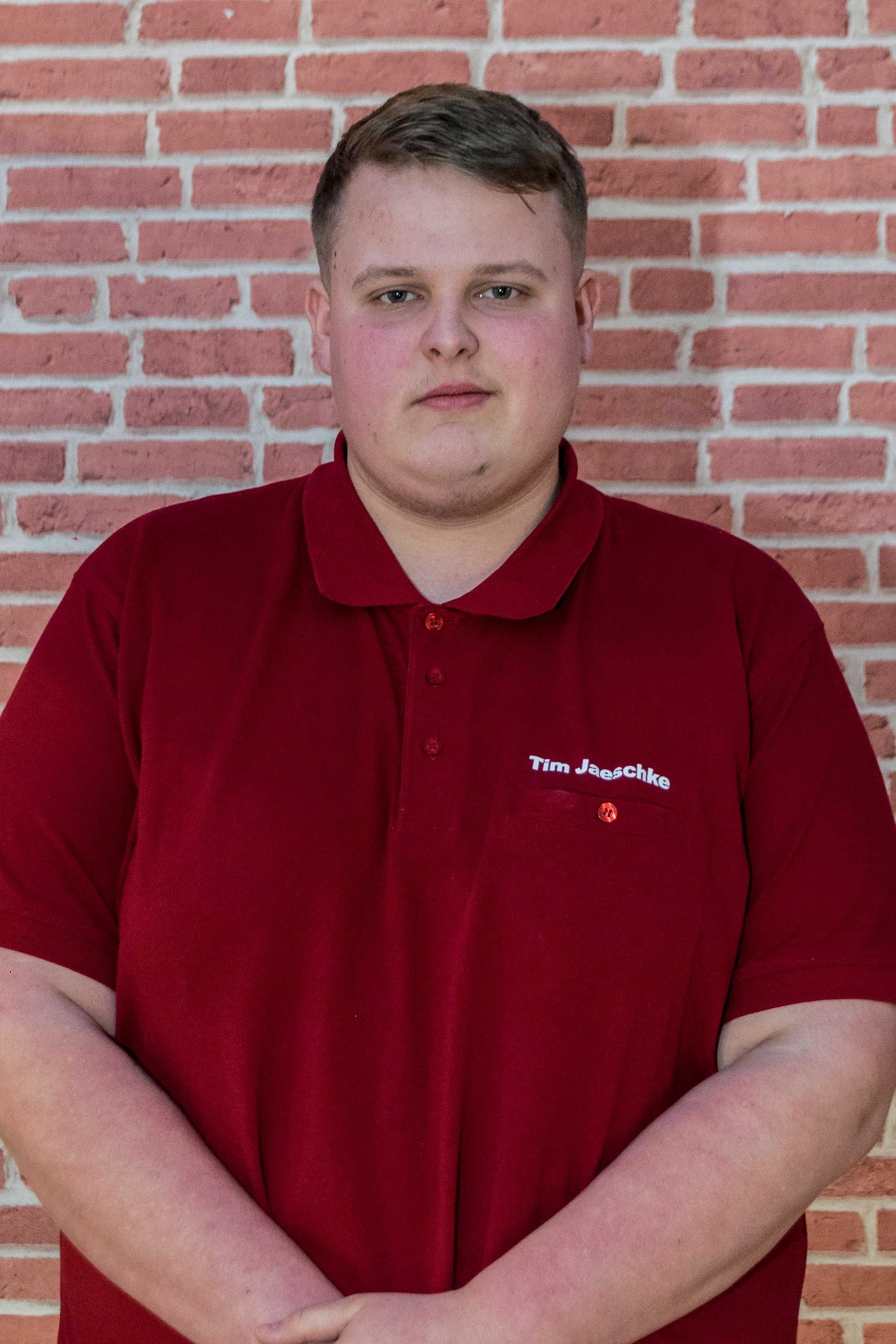 Ein Mann mit Schnurrbart steht vor einer Backsteinmauer. Portrait von Martin Holtermann