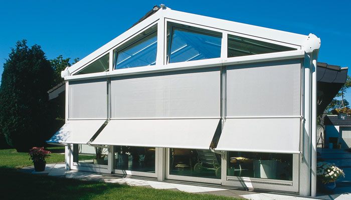 Ein Gebäude mit blau-weißen Markisen vor den Fenstern. Fensterbeschattung von Terrassenwelten Frank Merz