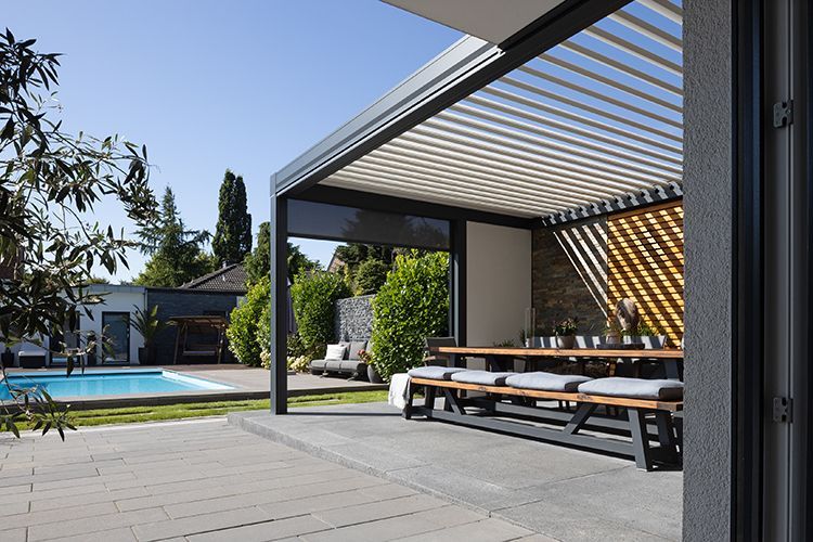 Eine Terrasse mit Tisch und Bänken unter einer Pergola neben einem Pool.