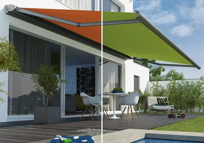 Zwei Markisen: orange eingefahren, grün ausgefahren, über einer Terrasse mit Gartenmöbeln.