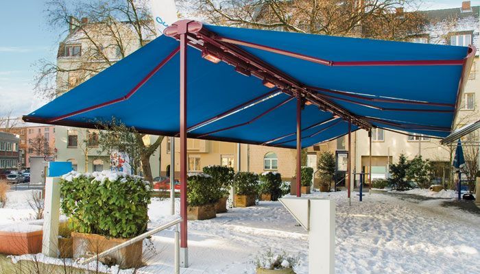 Eine blaue Markise bedeckt eine Terrasse im Schnee. Markisen von Terrassenwelten Frank Merz