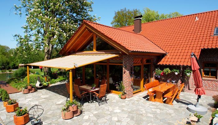 Ein Haus mit einem roten Dach und einer Terrasse mit Tisch und Stühlen