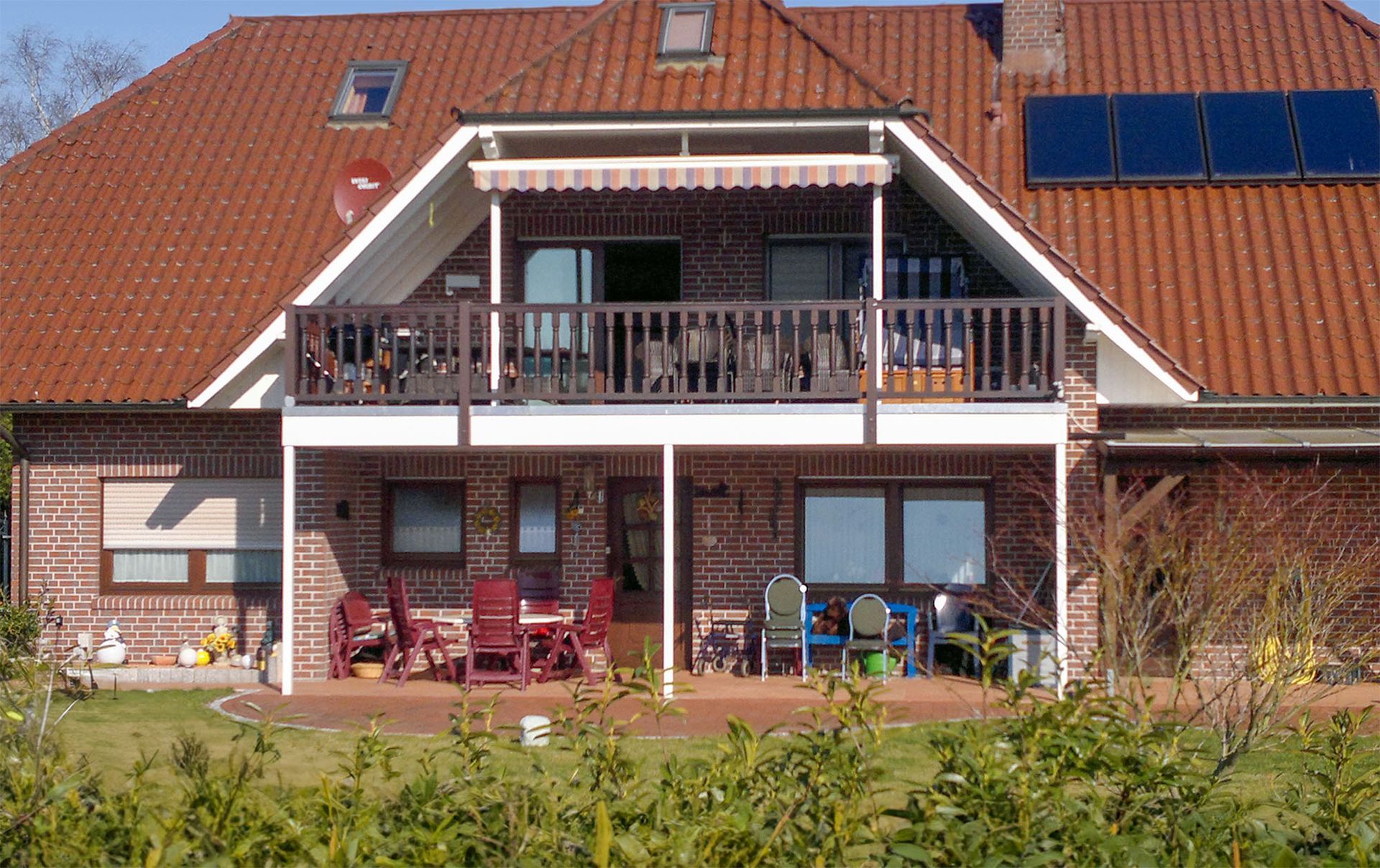 Ein großes Backsteinhaus mit Balkon und Sonnenkollektoren auf dem Dach. Vorherbild