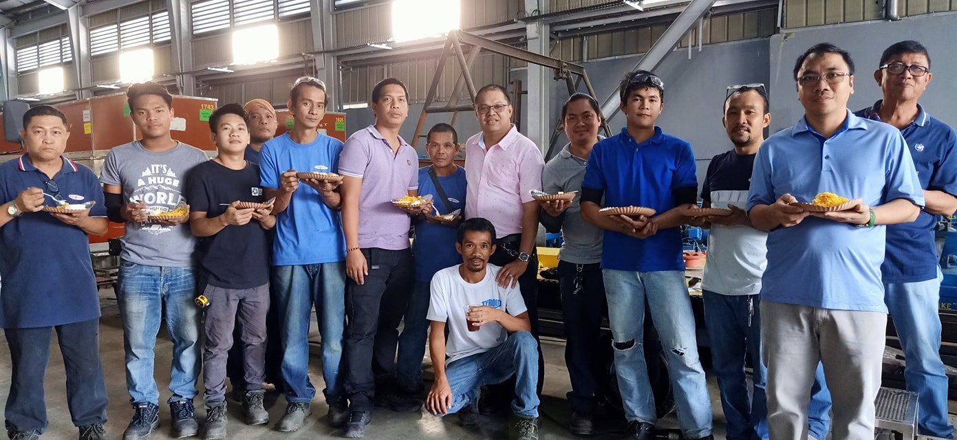 A group of men are posing for a picture in a factory.