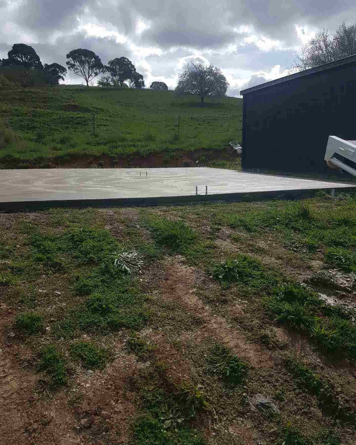 A Concrete Walkway Is Being Built In A Grassy Field Next To A Shed — Regional Concreting Solutions In Molong, NSW
