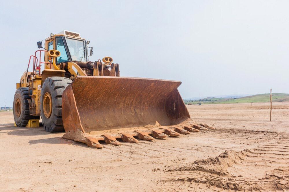 A Bulldozer Is Sitting In The Middle Of A Dirt Field — Regional Concreting Solutions In Molong, NSW