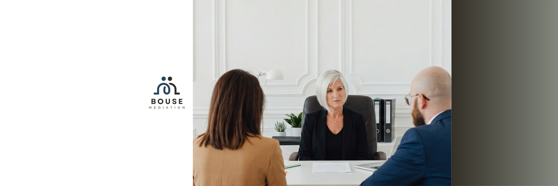 Three professionals sit at a desk in a bright, modern office during a meeting.