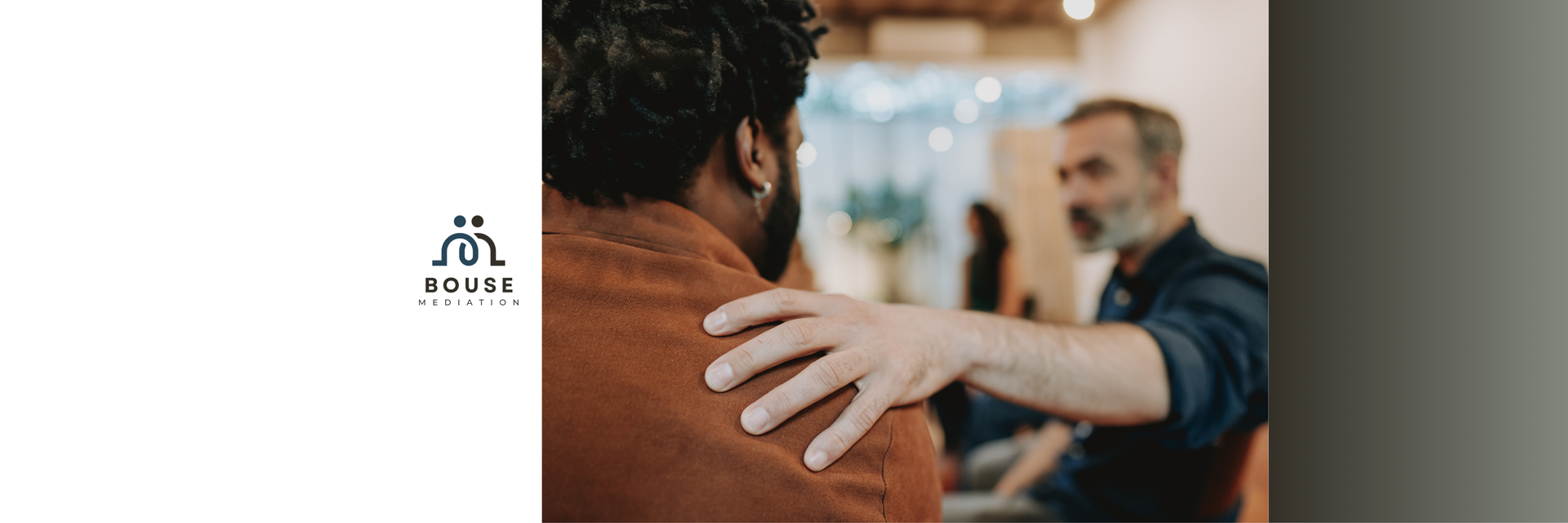 A person with a hand on their shoulder being comforted by another person in an office setting.