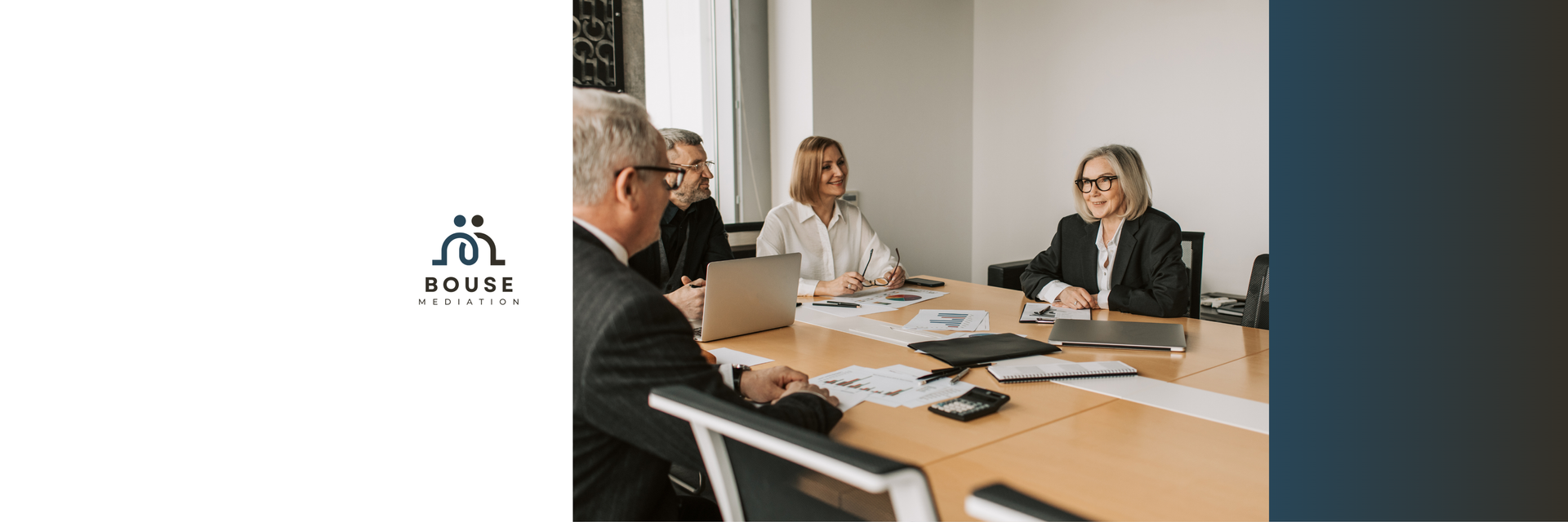 Four professionals sit at a wooden conference table in a modern, brightly lit office meeting, looking at documents.