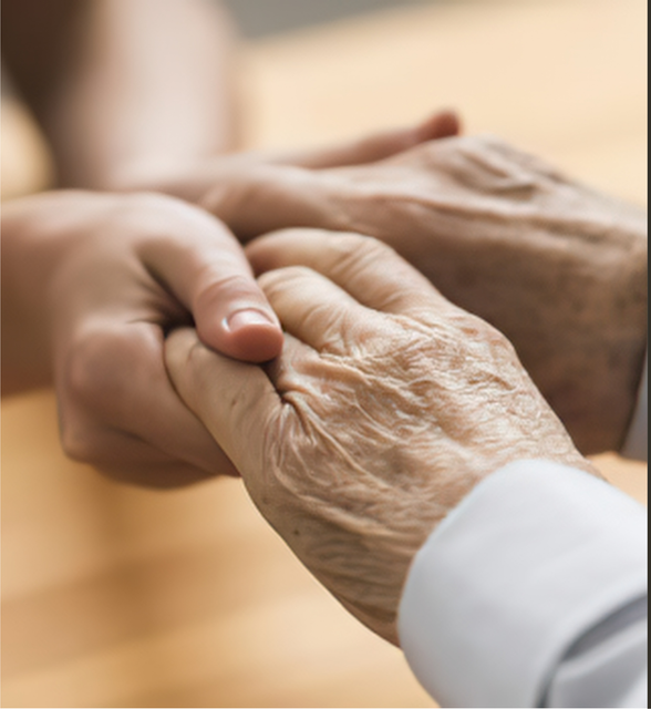 A young hand gently holding an elderly hand in a warm, soft-lit setting