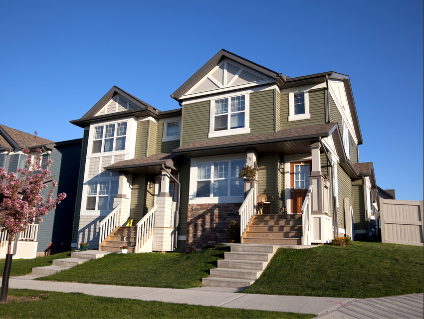 A modern green multi-family residential building exterior with a clear blue sky, next to a logo on a white background.