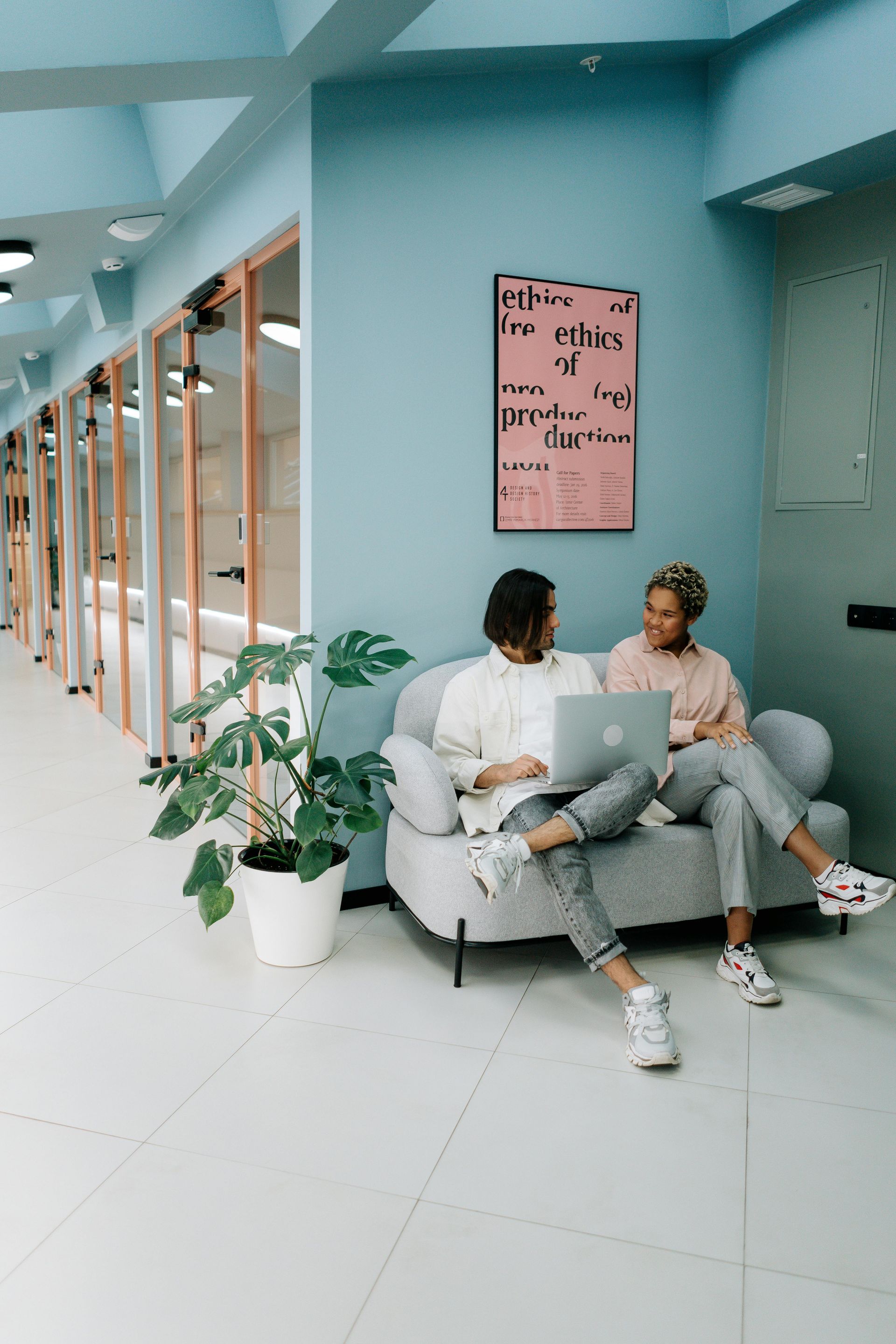 Four people in a meeting, two arguing. One man gestures, holding papers. Woman covers mouth, another sits, looking on.